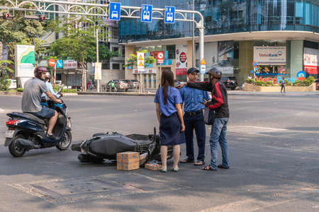 Ho Chi Minh City, Vietnam - March 12, 2019: Downtown street scenery Accident. Blue bus cuts off scooter, on the ground. Bus has fled the scene. Victim explains to police, Young woman confirms as witness.のeditorial素材
