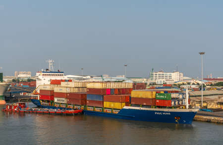Ho Chi Minh City, Vietnam - March 13, 2019: Tan Thuan port on Song Sai Gon river at sunset. Blue Phuc Hung container vessel with multi colored boxes and GLS Petrol barge fueling up along.のeditorial素材