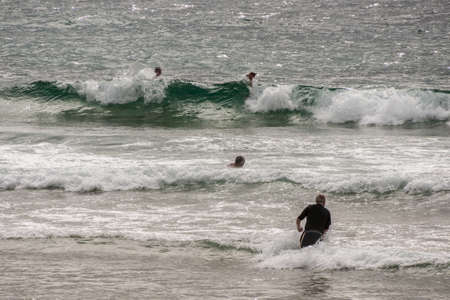 Newcastle, Australia - December 10, 2009: People surf the waves of the greenish South Pacific Ocean...