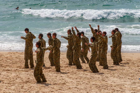Newcastle, Australia - December 10, 2009: Group of camouflage clad young Australian Marines exercise jumps on sandy beach at greenish water edge.のeditorial素材
