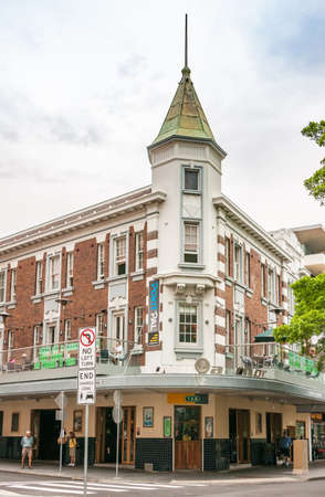 Newcastle, Australia - December 10, 2009: Historic Crown & Anchor hotel on corner of Hunter and Perkins street with its green roof tower under white cloudscape. People and green foliage.のeditorial素材