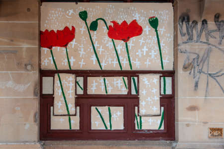 Newcastle, Australia - December 10, 2009: Closeup of wall painting showing crosses and red poppies on beige stone wall at WW1 35th infantry battalion memorial. Defacing graffiti nearby.のeditorial素材