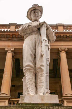 Newcastle, Australia - December 10, 2009: Closeup of white statue of soldier resting on rifle at WW1 35th infantry battalion memorial. Silver sky and beige classical building.のeditorial素材