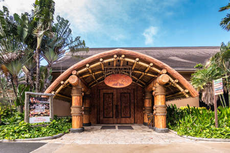 Laie, Oahu, Hawaii, USA. - January 09, 2020: Polynesian Cultural Center. Large wooden entrance to Island Buffet restaurant under blue sky with lots of green vegetation and foliage around.のeditorial素材