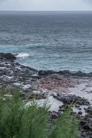 Koloa, Kauai, Hawaii, USA. - January 16, 2020: Gray-azure Pacific Ocean with black rocky coastline...