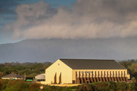 Nawiliwili, Kauai, Hawaii, USA. - January 16, 2020: Early morning light on large yellow Guardian Self Storage warehouse in port on green hill under brown cloudscape.のeditorial素材