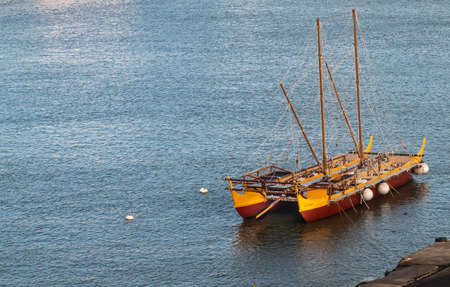 Nawiliwili, Kauai, Hawaii, USA. - January 16, 2020: Early morning light on yellow and maroon Namahoe replica of Pacific Islands Long Distance Canoe upon blue ocean water,のeditorial素材