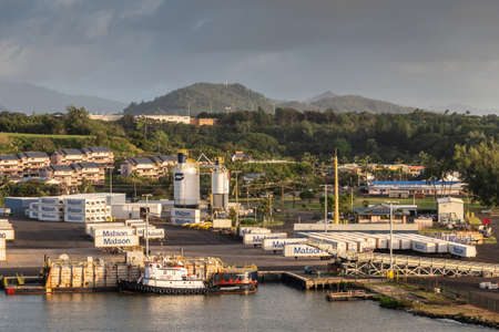 Nawiliwili, Kauai, Hawaii, USA. - January 16, 2020: Early morning light on dock in the port with Matson container yard. Green tree belt in back under brown and light blue sky. Tugboat and barge in front.のeditorial素材