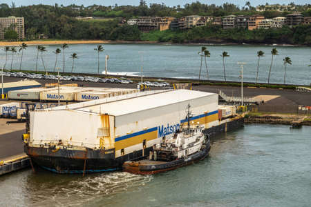 Nawiliwili, Kauai, Hawaii, USA. - January 17, 2020: Floating barge in port with white warehouse on top to cover shipping containers carries the Matson brand. Greenish ocean water. Green belt with housing.のeditorial素材