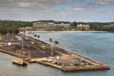 Nawiliwili, Kauai, Hawaii, USA. - January 17, 2020: South reef platfom of port built into sea water with Marriott Resort and beach in back, enveloped in green trees. Blue ocean water under gray cloudscape.のeditorial素材