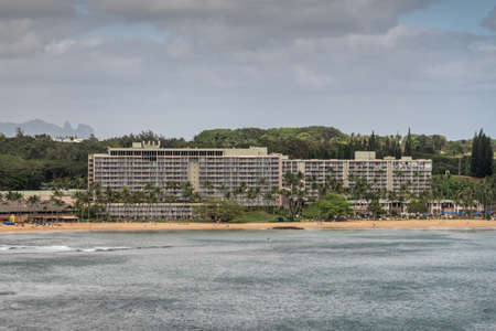 Nawiliwili, Kauai, Hawaii, USA. - January 17, 2020: Marriott Beach Resort buildings surrounded by green trees adjacent to the port. Gray ocean water under gray cloudscape.のeditorial素材