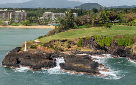 Nawiliwili, Kauai, Hawaii, USA. - January 17, 2020: Wide view over Marriott beach resort, green golf course with Kukii lighthouse or beacon on black lava rock up front. Greenish ocean water.のeditorial素材