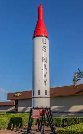 Oahu, Hawaii, USA. - January 10, 2012: Pearl Harbor. Red tipped gray US Navy Polaris submarine-launched ballistic missile against deep blue sky on display. brown building and green foliage in back.のeditorial素材