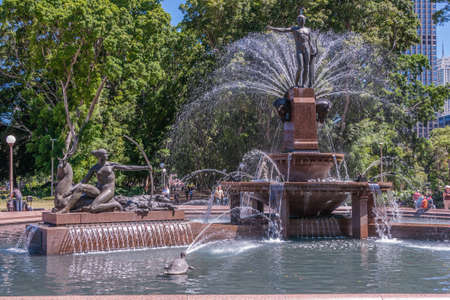 Sydney, Australia - December 11, 2009: Archibald fountain in full operation with archer statue extra. Spouting water, green foliage and people in sun.のeditorial素材
