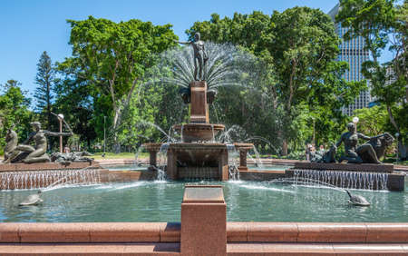 Sydney, Australia - December 11, 2009: Full composition of Archibald fountain in full operation. Spouting water, green foliage, blue sky and people in sun.のeditorial素材
