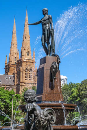 Sydney, Australia - December 11, 2009: Portrait of Apollo statue at Archibald fountain in full operation. Spouting water, green foliage, Saint Mary Cathedral and blue sky.のeditorial素材