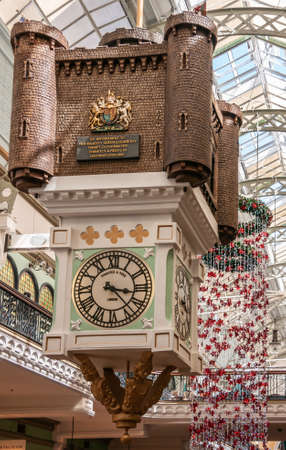 Sydney, Australia - December 11, 2009: Beige-green clock with castle on top hanging from ceiling inside Queen Victoria building shopping mall. Christmas decoration in back.のeditorial素材