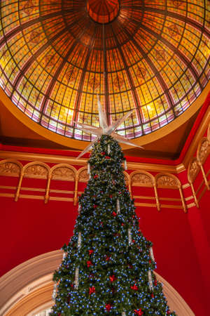 Sydney, Australia - December 11, 2009: Decorated green christmas tree under colorful giant glass dome surrounded by red walls inside Queen Victoria building shopping mall.のeditorial素材