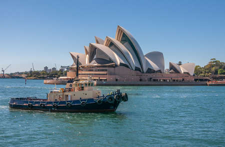 Sydney, Australia - December 11, 2009: Opera House. Black-blue-beige tugboat in front under blue sky and on azure bay water.のeditorial素材