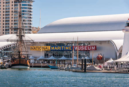 Sydney, Australia - December 11, 2009: Darling Harbour. Closeup of National Maritime Museum building seen from upon the water under blue sky. Hotel building in back. Tall ship docked.のeditorial素材
