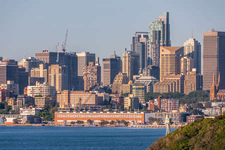 Sydney, Australia - December 11, 2009: City skyline with multiple skyscrapers and tallest World Tower. Navy pier and red warehouse-office on shore of bay. Green foliage of Bradleys Head.のeditorial素材