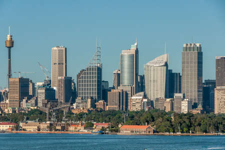 Sydney, Australia - December 11, 2009: City skyline with multiple skyscrapers and tallest Eye tower behind Navy pier and red roofed buildings and Green foliage of Garden Island.のeditorial素材