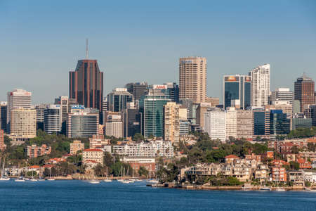 Sydney, Australia - December 11, 2009: North Sydney cityscape with office towers of businesses behind Neutral Harbour and its anchored white yachts. Lots of houses and green foliage.のeditorial素材