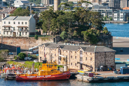 Sydney, Australia - December 11, 2009: Light brown stone historic building of NSW Port Authority on dock at Walsh Bay, Some of their boats are docked. Green foliage in back and wider cityscape.のeditorial素材