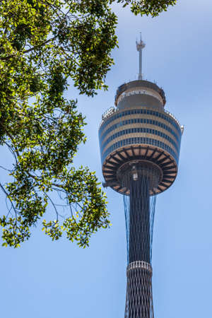 Sydney, Australia - December 11, 2009: Sydney Tower Eye, Closeup of heavy top section with part of elevator shaft against light blue sky. Green foliage in corner of photo.のeditorial素材