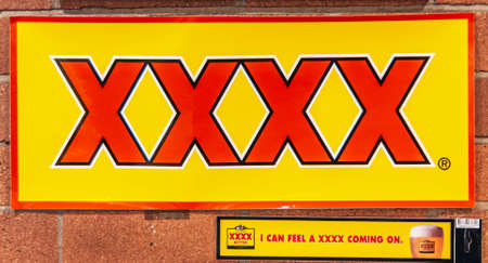 Brisbane, Australia - December 8, 2009: Red on yellow XXXX beer sign against red brick wall. Slogan...