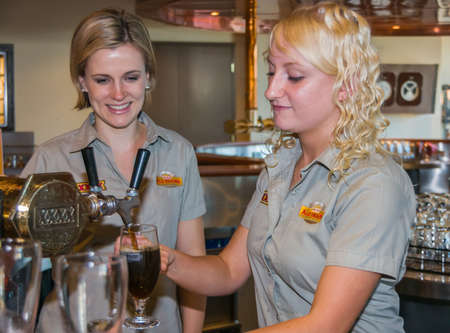 Brisbane, Australia - December 8, 2009: Castlemaine Perkins brewery. 2 young women bar servants tapping beer at The bar of visitor centre.のeditorial素材