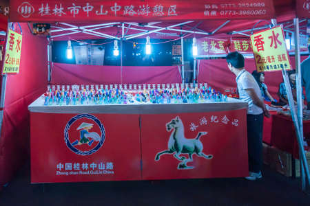 Guilin, China - May 9, 2010: Zhong Shan Road evening market. Small glass perfume bottles in different colros at booth with strong light at night. Vendor present.のeditorial素材