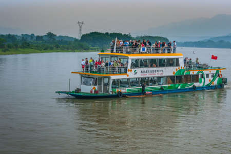 Guilin, China - May 10, 2010: Along Li River. White-orange-green overloaded tourist sightseeing boat...