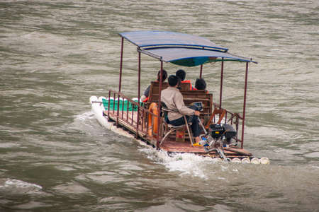 Guilin, China - May 10, 2010: Along Li River. Closeup of 4-person small ferry boat, a raft with a motor, on greenish water.のeditorial素材