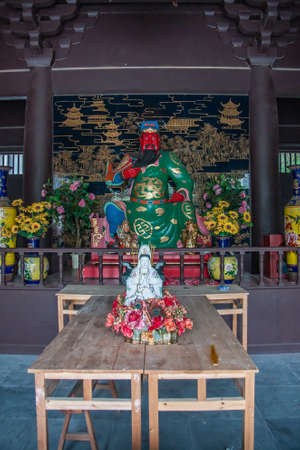Guilin, China - May 11, 2010: Qixia Buddhist Temple in Seven Star Park. Statues of Red-faced, green-golden garb, Guan Yu God of War surrounded by flowers and small Guan up front.のeditorial素材