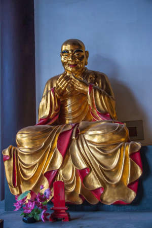 Guilin, China - May 11, 2010: Qixia Buddhist Temple in Seven Star Park. Golden statue of Pra Asito, Chinese Buddhist saint. against blue blackdrop.のeditorial素材