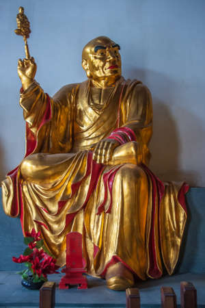 Guilin, China - May 11, 2010: Qixia Buddhist Temple in Seven Star Park. Golden statue of Pra Lo Koo Lo, Chinese Buddhist saint against blue blackdrop.のeditorial素材
