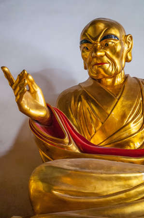 Guilin, China - May 11, 2010: Qixia Buddhist Temple in Seven Star Park. Chest and hand closeup of Golden statue of arhat, Chinese Buddhist saint. against blue blackdrop.のeditorial素材