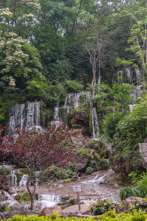 Guilin, China - May 11, 2010: Seven Star Park. Portrait of waterfall scenery with white streams set in green foliage with rocks.の写真素材