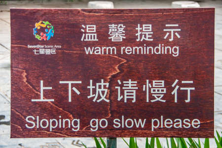 Guilin, China - May 11, 2010: Seven Star Park. White on brown warning sign about going slow on slope with funny spelling error in English.のeditorial素材