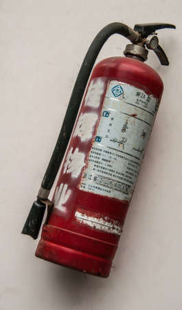 Guilin, China - May 10, 2010: Downtown. Closeup of red fire extinguisher against beige wall. Black...