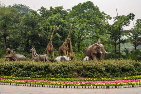 Chongqing, China - May 9, 2010: Inside zoo or animal park. grouip of statues featuring hippopotamus, zebra, giraffe, panda, elephant and monkey in green foliage and flower environment.のeditorial素材