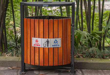 Chongqing, China - May 9, 2010: Inside zoo or animal park. Brown-green Combination trash bin for regular and recyclable garbage, with sign and in front of green foliage.のeditorial素材