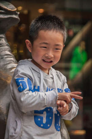Shanghai, China - May 4, 2010: Closeup of young boy in gray-blue training outfit pretends to shoot,...