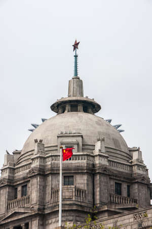 Shanghai, China - May 4, 2010: Closeup of gray-brown top with dome of HSBC bank with red Chinese flag in front, star on top, against silver sky.のeditorial素材