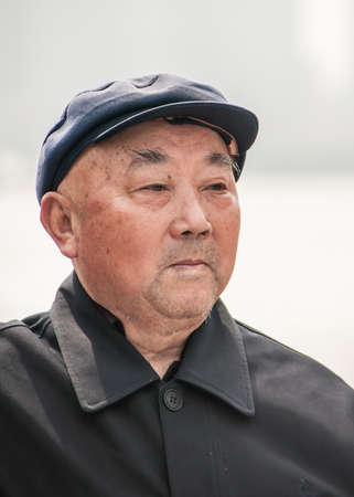 Shanghai, China - May 4, 2010: Closeup of face of older balding senior man with black shirt and black hat.のeditorial素材