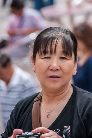 Shanghai, China - May 4, 2010: Closeup of face of woman with dressed in black with Samsung camera in her hands.のeditorial素材
