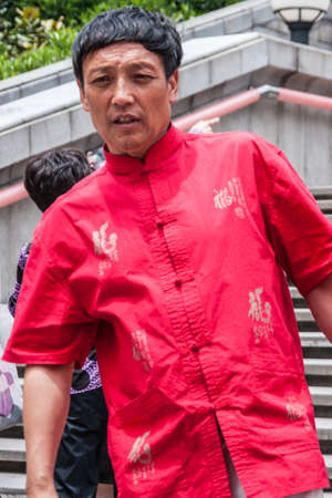 Shanghai, China - May 4, 2010: Portrait of young man in traditional red shirt comes down the steps.のeditorial素材