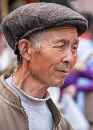 Shanghai, China - May 4, 2010: Portrait closeup of older senior man with big brown had on. Gray turtle neck shirt and beige vest.のeditorial素材