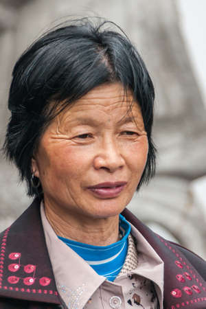 Shanghai, China - May 4, 2010: Portrait closeup of face of woman with short black hair, and three layers of clothing: blue, beige, maroon.のeditorial素材